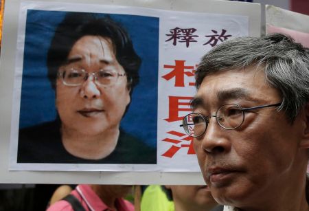 A picture of Hong Kong bookseller Gui Minhai is shown on a placard beside another bookseller, Lam Wing-kee, who criticized Gui’s prison sentence announced by China. Kin Cheung/Associated Press/File 2016/Associated Press